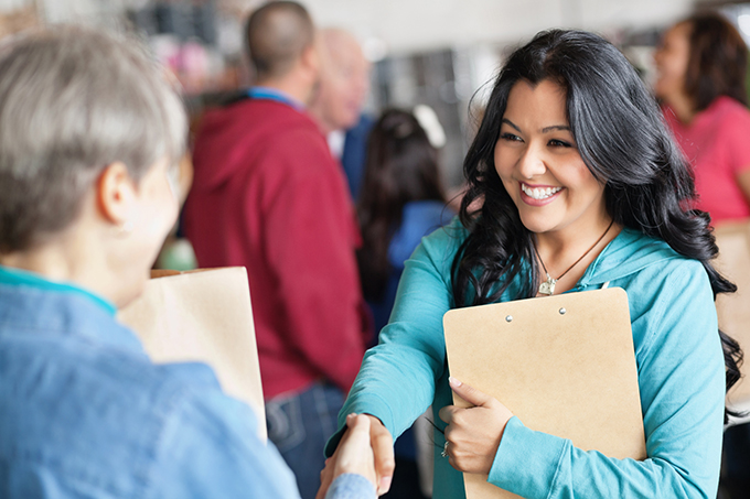 Latina volunteer greeting a woman at donation facility.