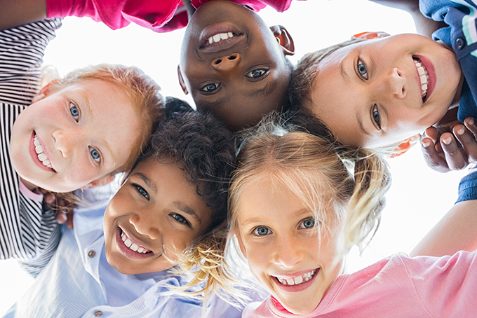 Group of smiling multiracial kids embracing in a circle.